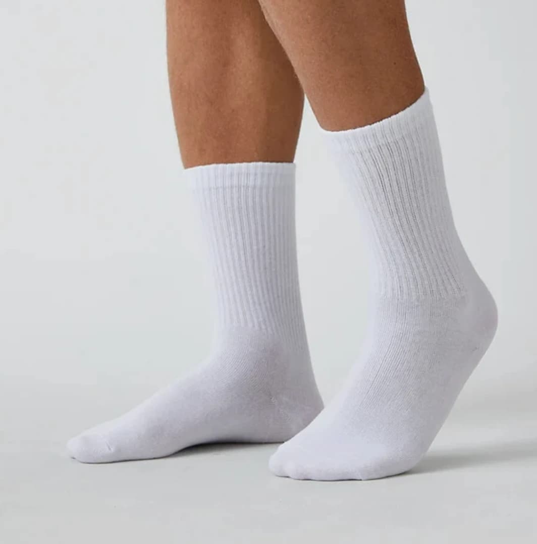 Weiße Snocks-Socken an zwei Füßen vor hellem Hintergrund